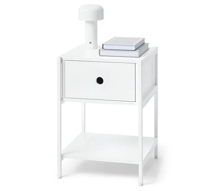 Table de chevet blanche avec un tiroir, une lampe et deux livres dessus.