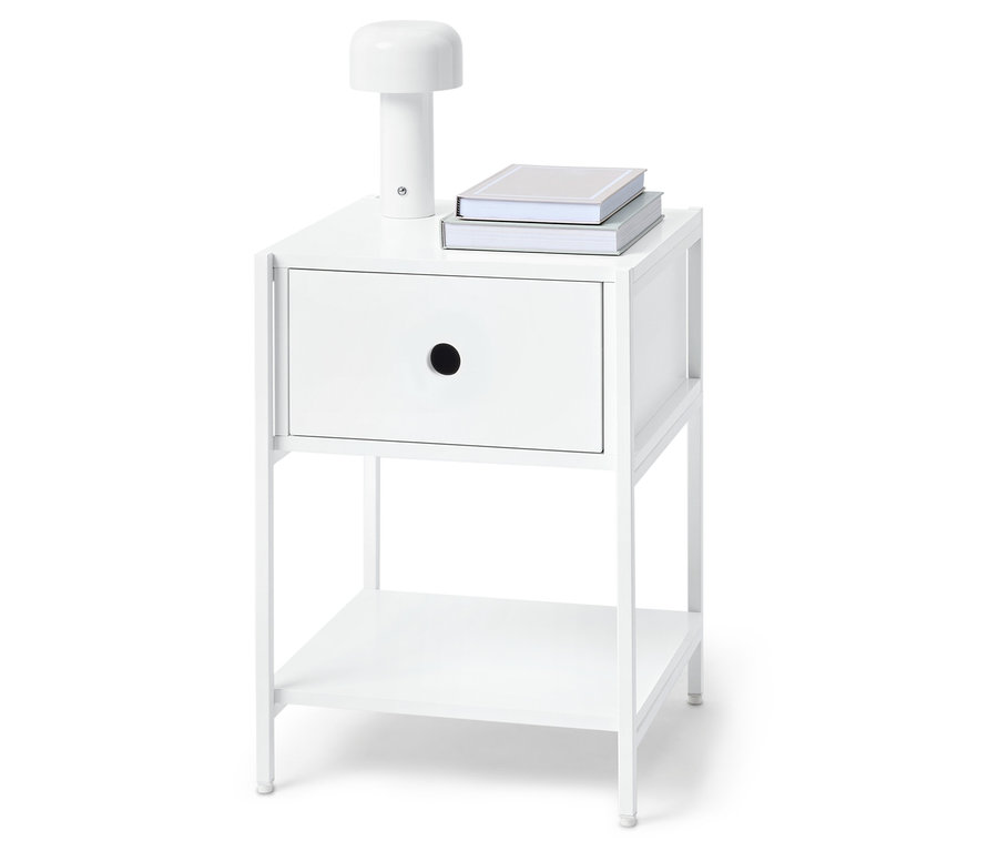 Table de chevet blanche avec un tiroir, une lampe et deux livres dessus.