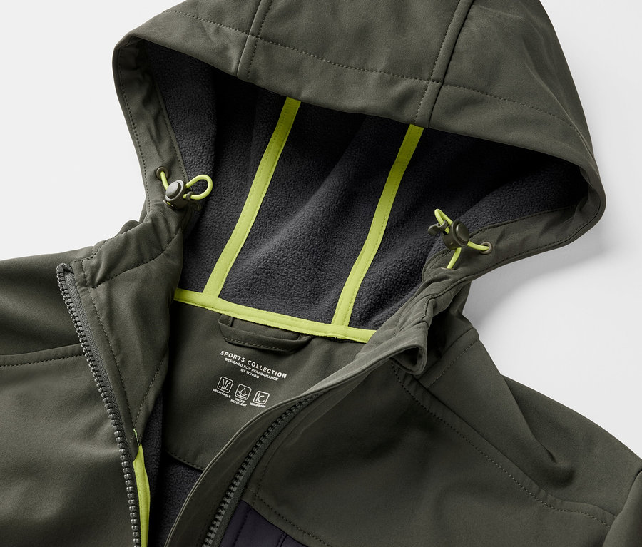 Gros plan sur une veste en softshell kaki avec capuche et détails jaune néon.