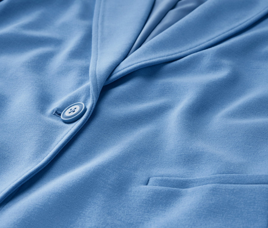Gros plan sur un blazer en jersey bleu clair avec un bouton et une poche.