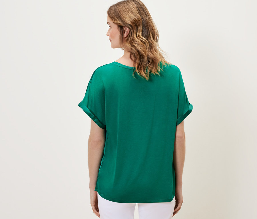 Femme vue de dos portant une blouse bimatière turquoise.
