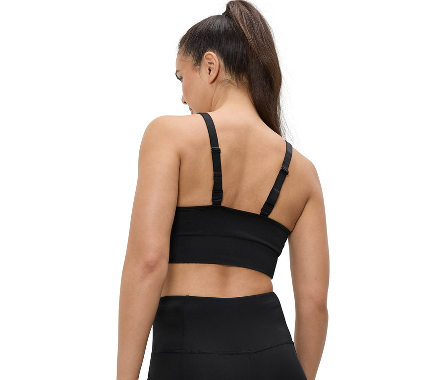 Vue arrière d'une femme avec une queue de cheval portant un soutien-gorge de sport et un legging noirs.