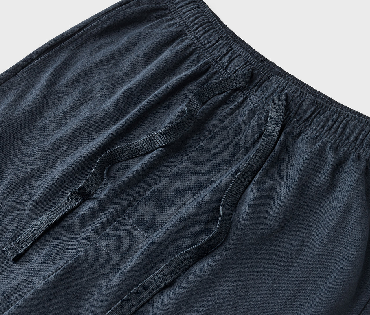 Gros plan sur un pantalon de survêtement bleu marine avec cordon de serrage à la taille.