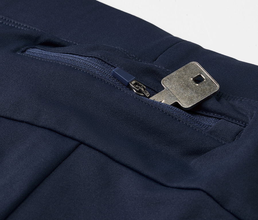 Détail d'un legging de sport coupe-vent bleu avec une clé dans la poche zippée.