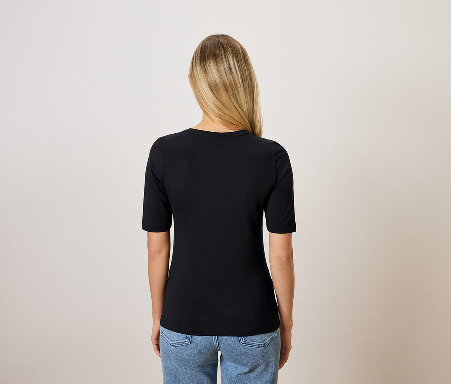 Vue arrière d'une femme blonde portant un t-shirt noir et un jean bleu.