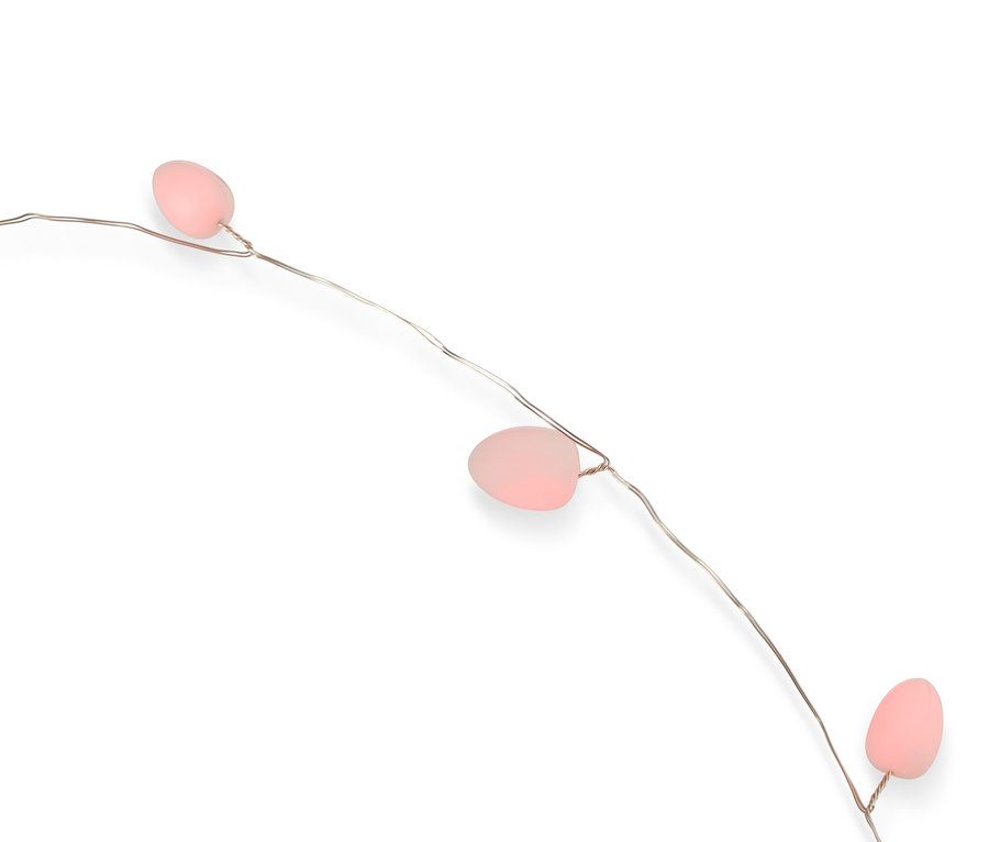 Gros plan d'une guirlande lumineuse avec trois œufs roses sur un mince fil d'argent sur fond blanc.