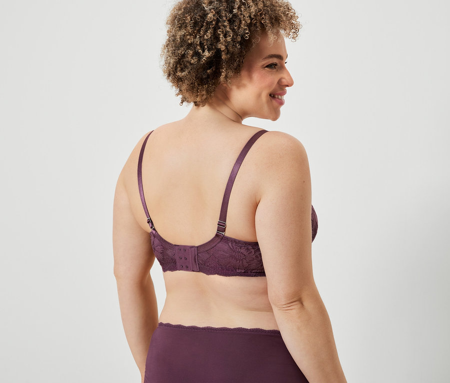 Femme portant un soutien-gorge et une culotte en dentelle bordeaux, vue de dos.