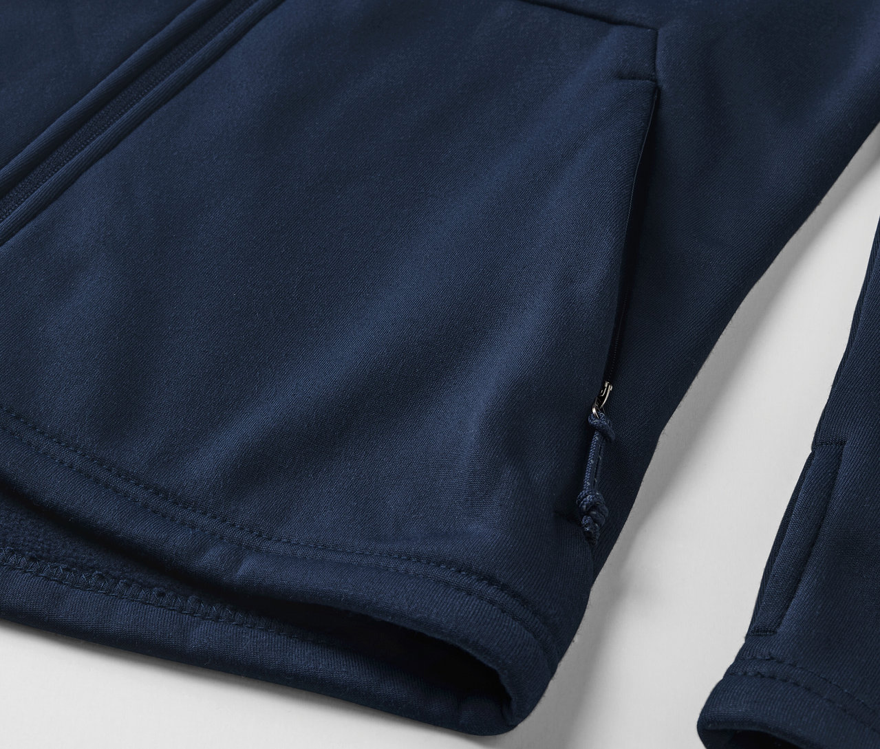 Détail d'un sweat-shirt zippé bleu marine avec poches.