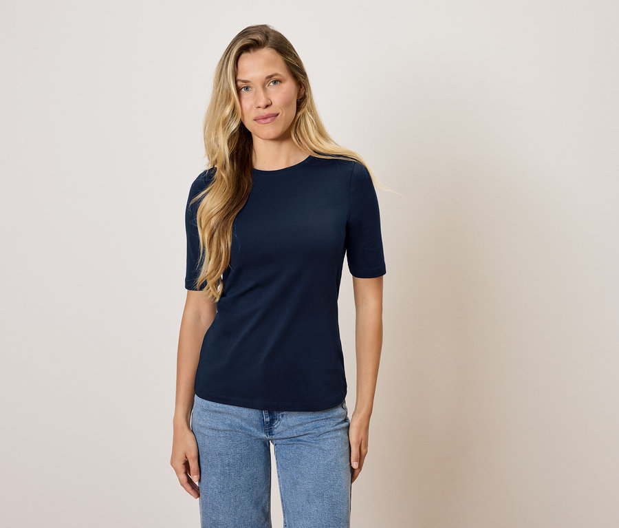 Une femme debout portant un t-shirt bleu marine et un jean.