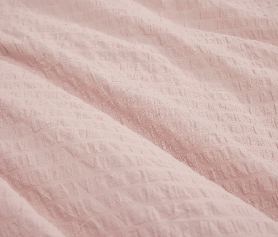 Gros plan d'un tissu rose clair texturé.