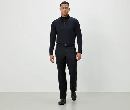 Un homme marche vers l'avant, portant un t-shirt noir à manches longues, un pantalon noir et des chaussures noires.