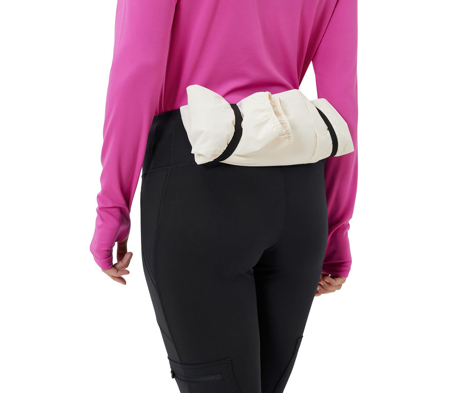 Une femme porte un collant d’extérieur noir et une veste crème autour de la taille.