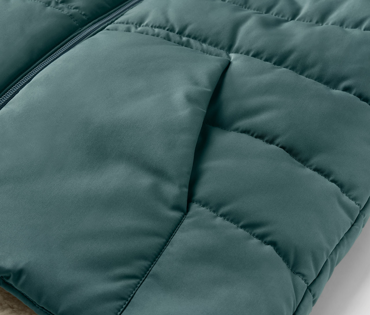 Détail d'un gilet sans manches matelassé en teddy pour enfant avec poche.