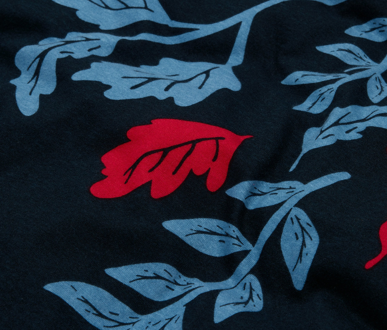 Gros plan d'un tissu bleu marine avec un motif intégral de feuilles bleues et des accents rouges.