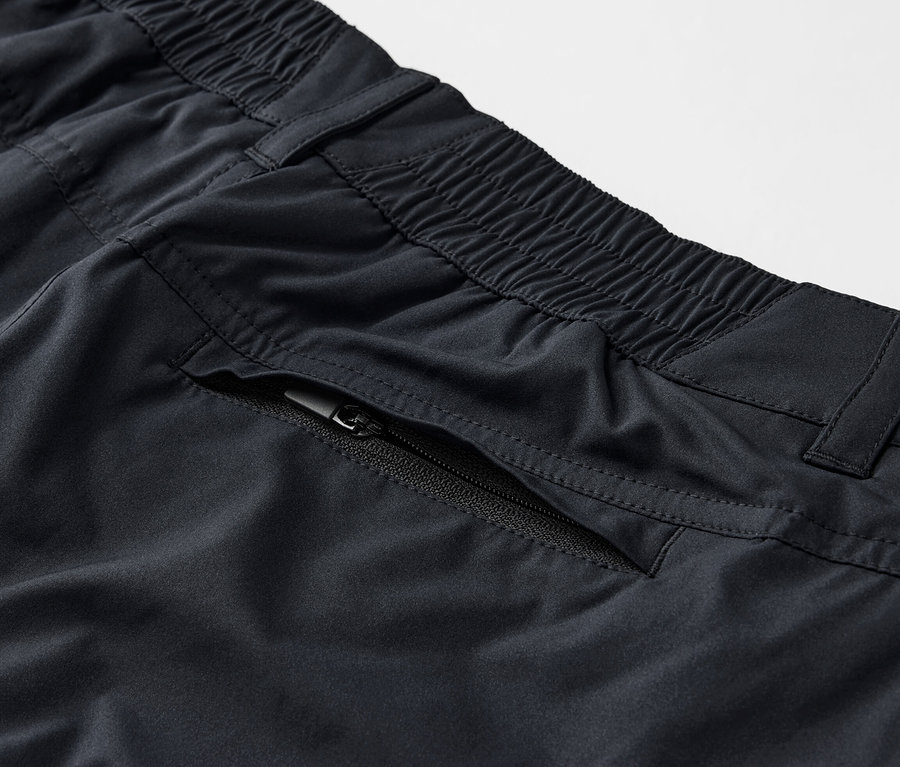 Gros plan sur un pantalon fonctionnel 2 en 1 noir avec une poche zippée.