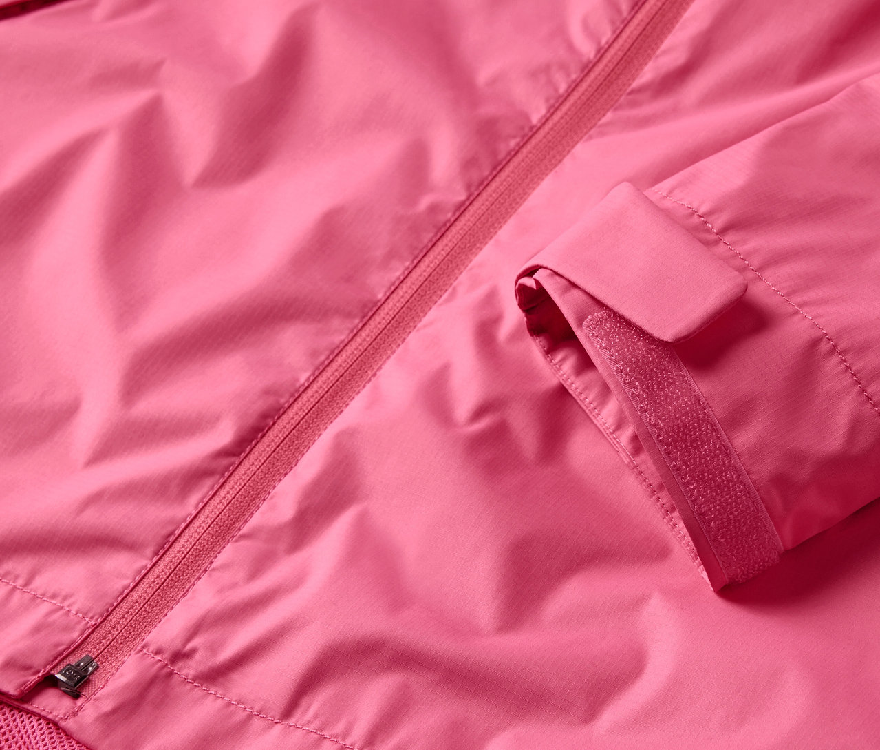 Gros plan sur une veste de pluie rose avec une fermeture éclair et une manche.