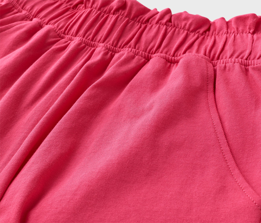 Gros plan sur un short rose avec une taille élastiquée et une poche.