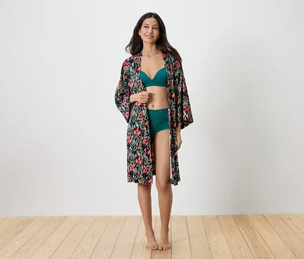 Femme portant un soutien-gorge vert et des sous-vêtements verts avec une robe de chambre imprimée par-dessus.