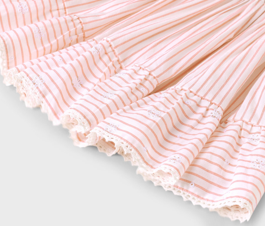 Gros plan sur l'ourlet d'une jupe à rayures roses avec une garniture en dentelle.