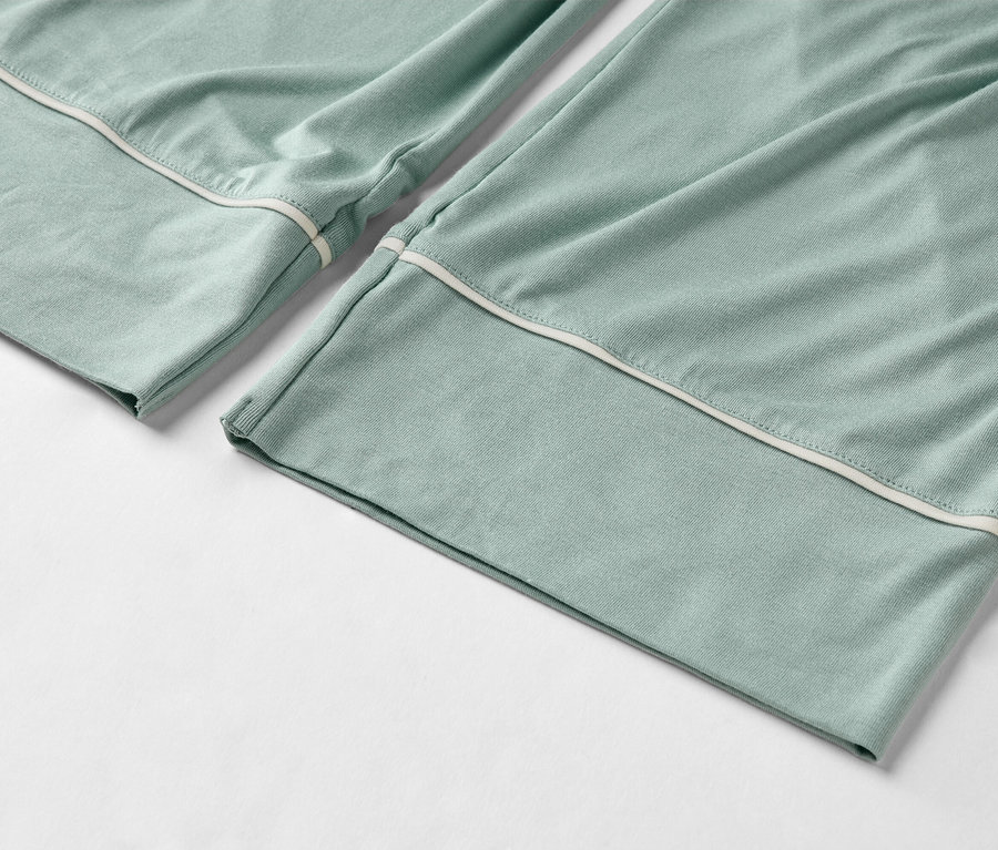 Gros plan d'un pantalon de pyjama vert clair avec une bordure blanche à l'ourlet.