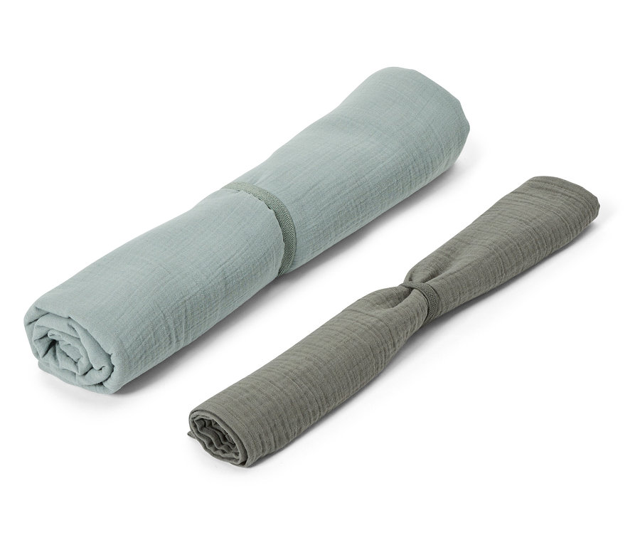 Deux langes en mousseline enroulés en bleu et gris reposent sur un fond blanc.