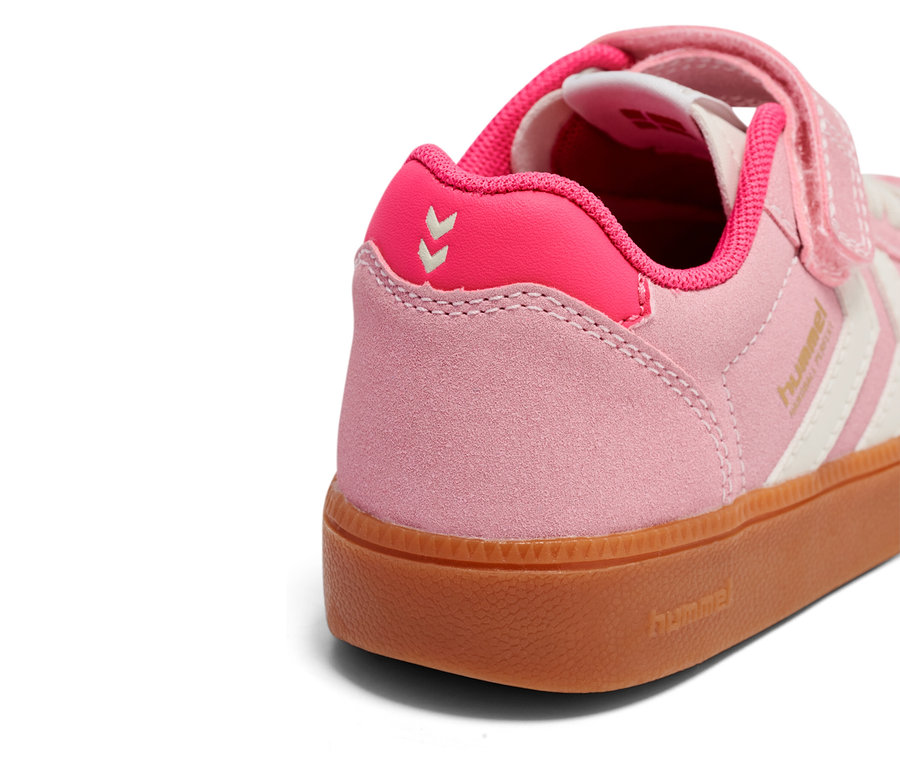Gros plan d'une basket Hummel rose et blanche avec fermeture Velcro et semelle en caoutchouc marron.