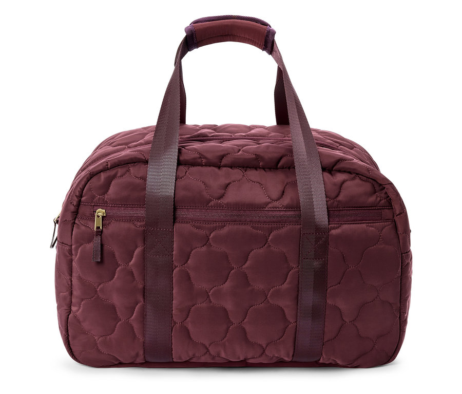 Gros plan d'un sac de voyage bordeaux matelassé avec des poignées et une poche zippée.