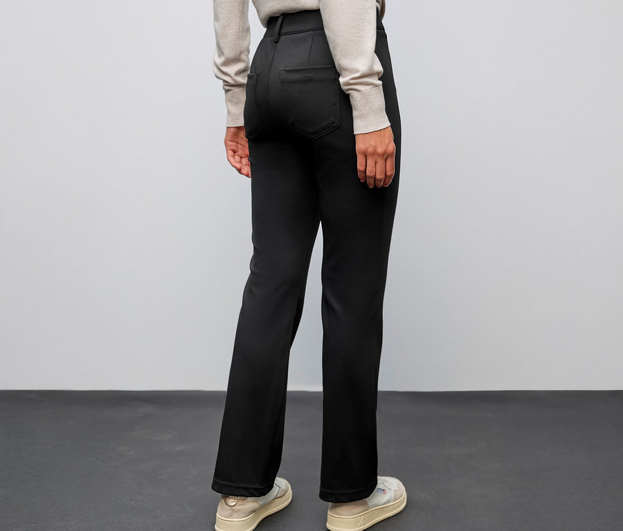 Personne vue de dos, portant un pantalon bootcut Street One noir et des chaussures claires.