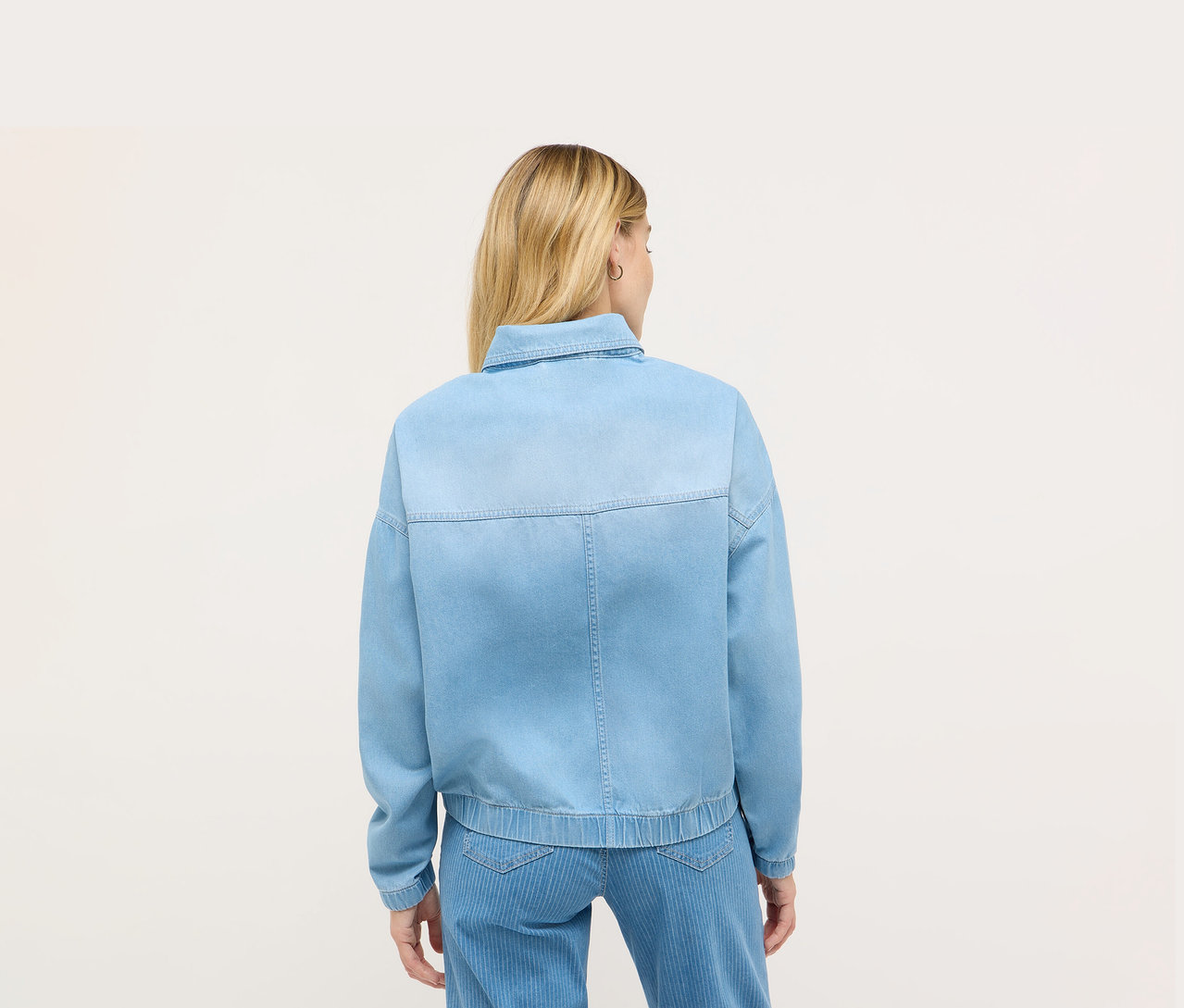 Vue arrière d'une femme blonde portant une veste en jean bleue Angels.