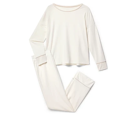 Un pyjama couleur crème à manches longues et pantalon est posé sur un fond blanc.