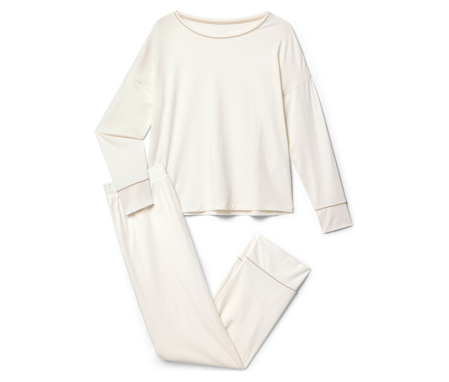 Un pyjama couleur crème à manches longues et pantalon est posé sur un fond blanc.