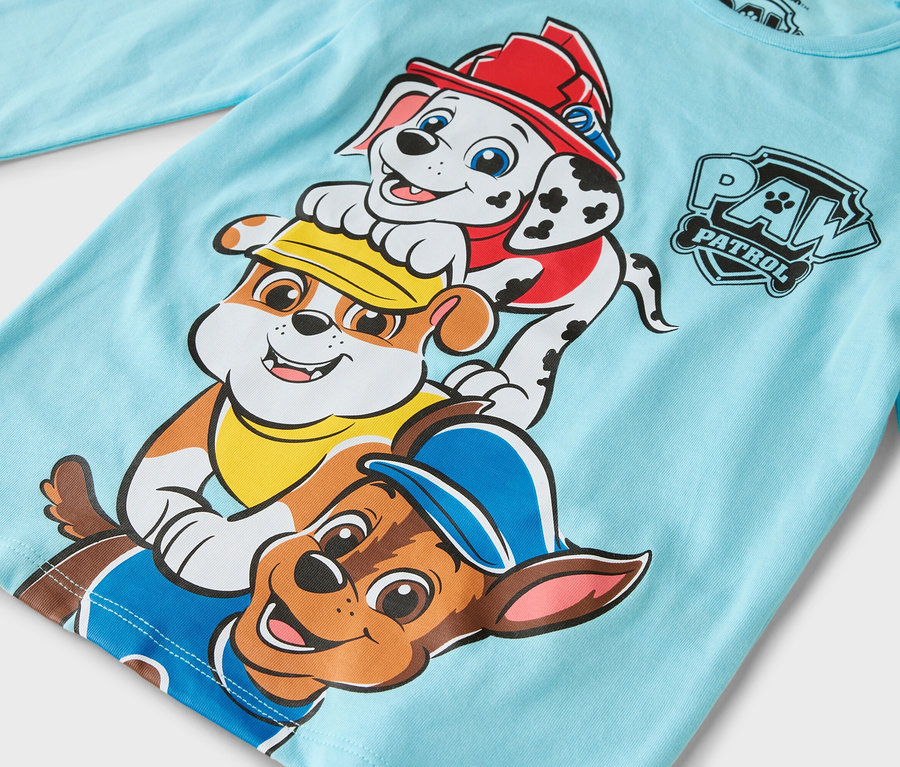 Sur le t-shirt à manches longues bleu clair figurent les personnages de la Pat' Patrouille : Marcus, Ruben et Chase.