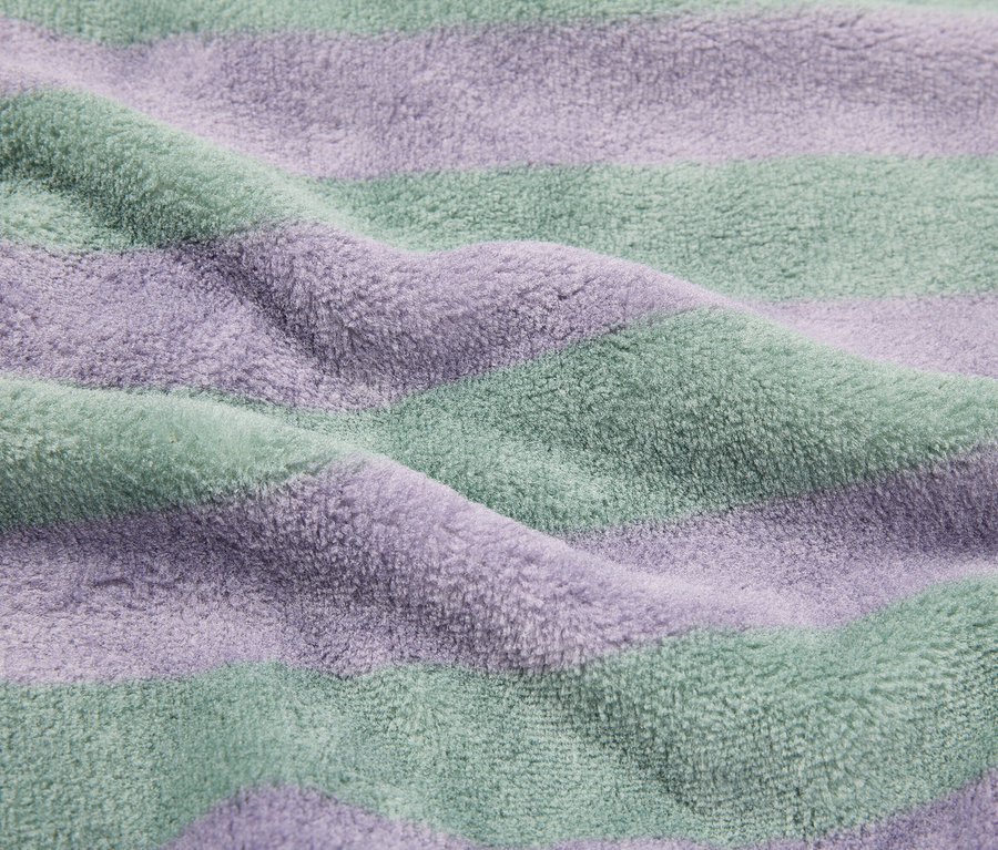 Gros plan d'une serviette éponge rayée violette et verte.
