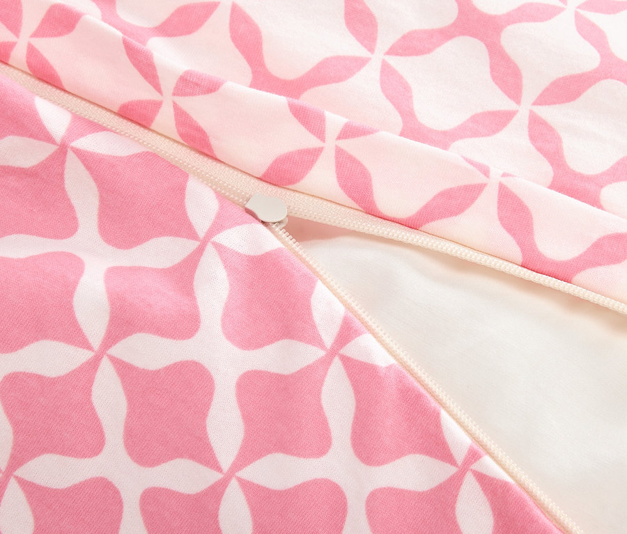 Gros plan d'une fermeture éclair partiellement ouverte sur un tissu à motifs rose et blanc.