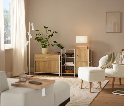 Scène d'intérieur avec un tapis beige »Cosmo«, un fauteuil bouclette avec pieds en bois et une lampe de table avec pied en bois.