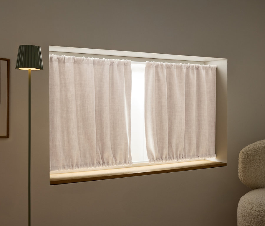 Vue d'une fenêtre avec des rideaux beiges, un lampadaire vert et une œuvre d'art abstraite au mur.