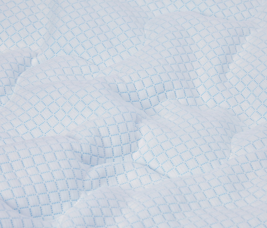 Gros plan d'un matelas blanc avec un motif losanges bleu clair et une surface matelassée.