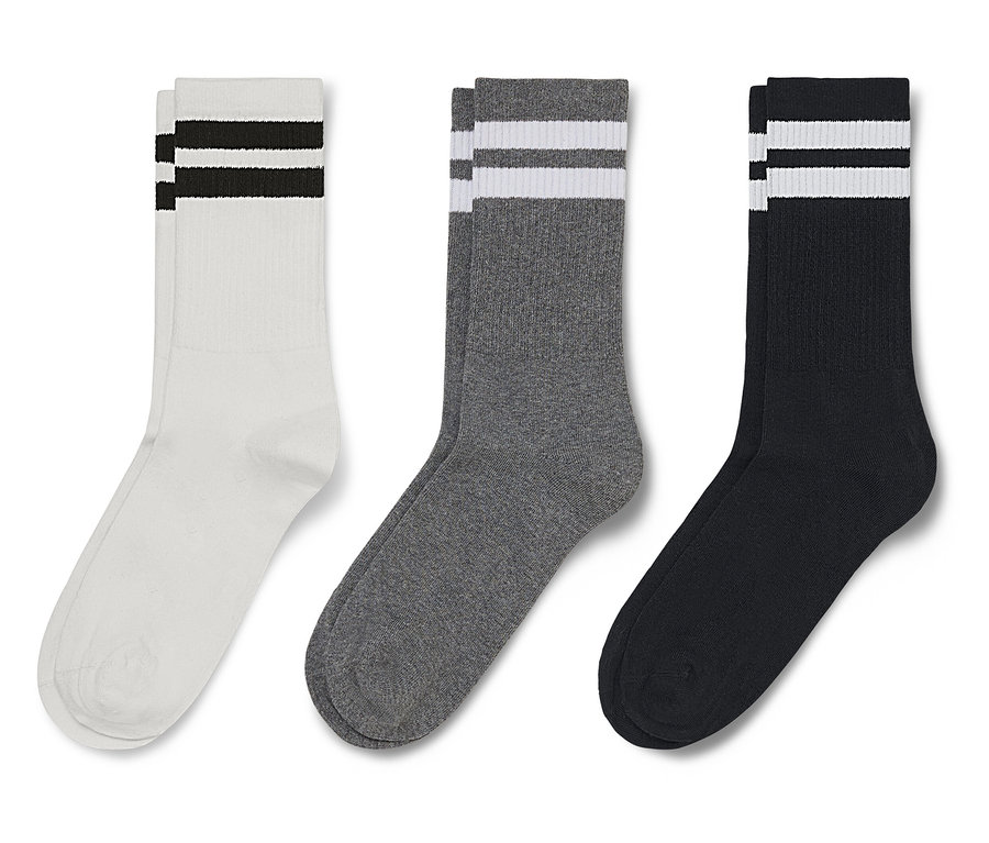 Trois paires de chaussettes sont côte à côte : blanches à rayures noires, grises à rayures blanches et noires à rayures blanches.