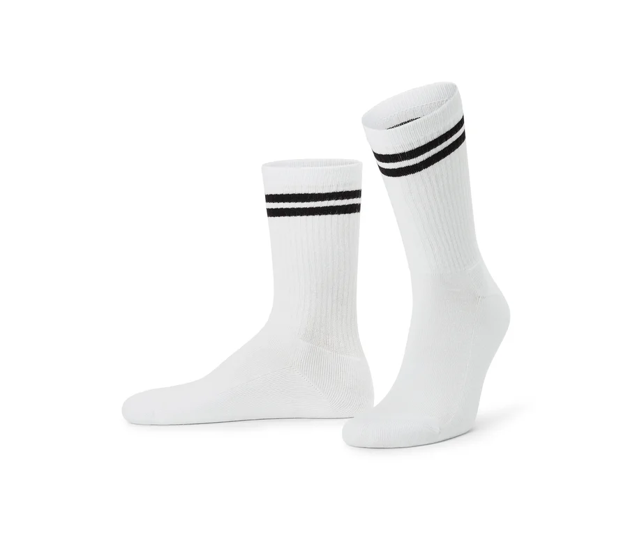 Deux chaussettes blanches avec deux rayures noires près du revers, l'une posée à plat, l'autre debout.