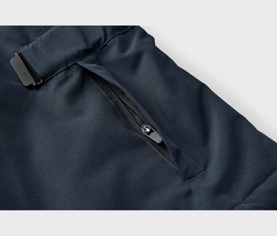 Gros plan sur un tissu bleu foncé avec une poche zippée noire partiellement ouverte et une sangle à boucle noire.