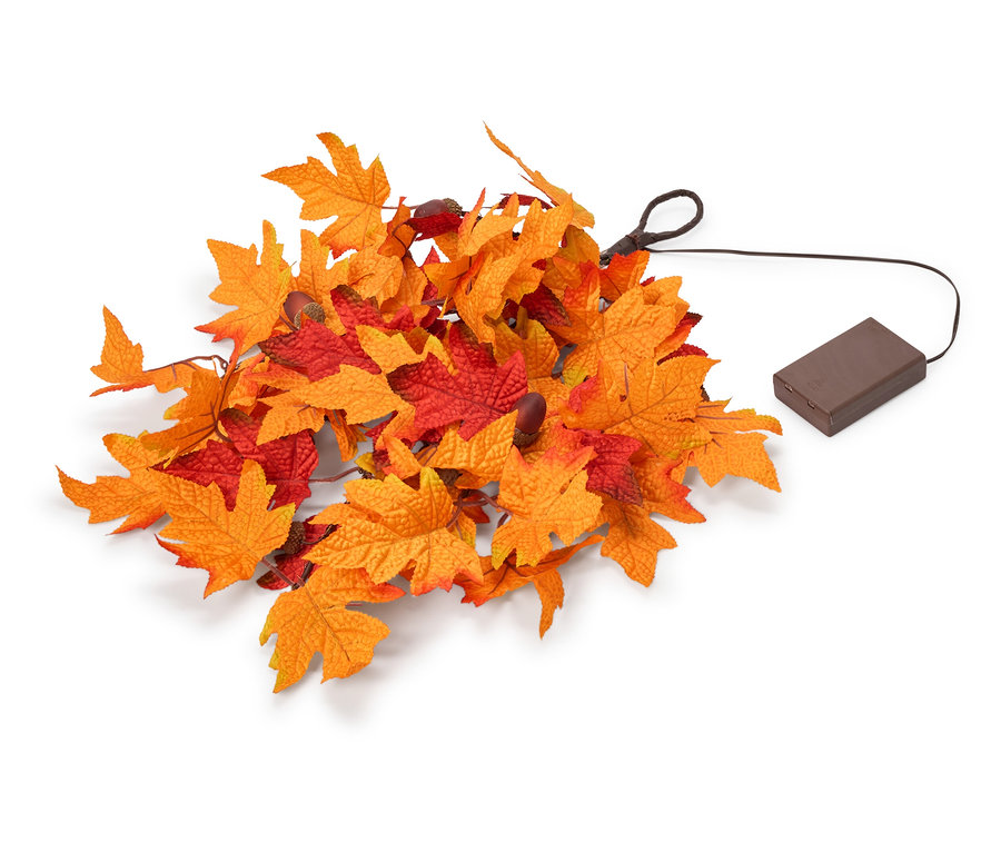 Un amas de feuilles d'automne artificielles orange et rouges, avec un fil noir menant à un boîtier de piles rectangulaire marron.