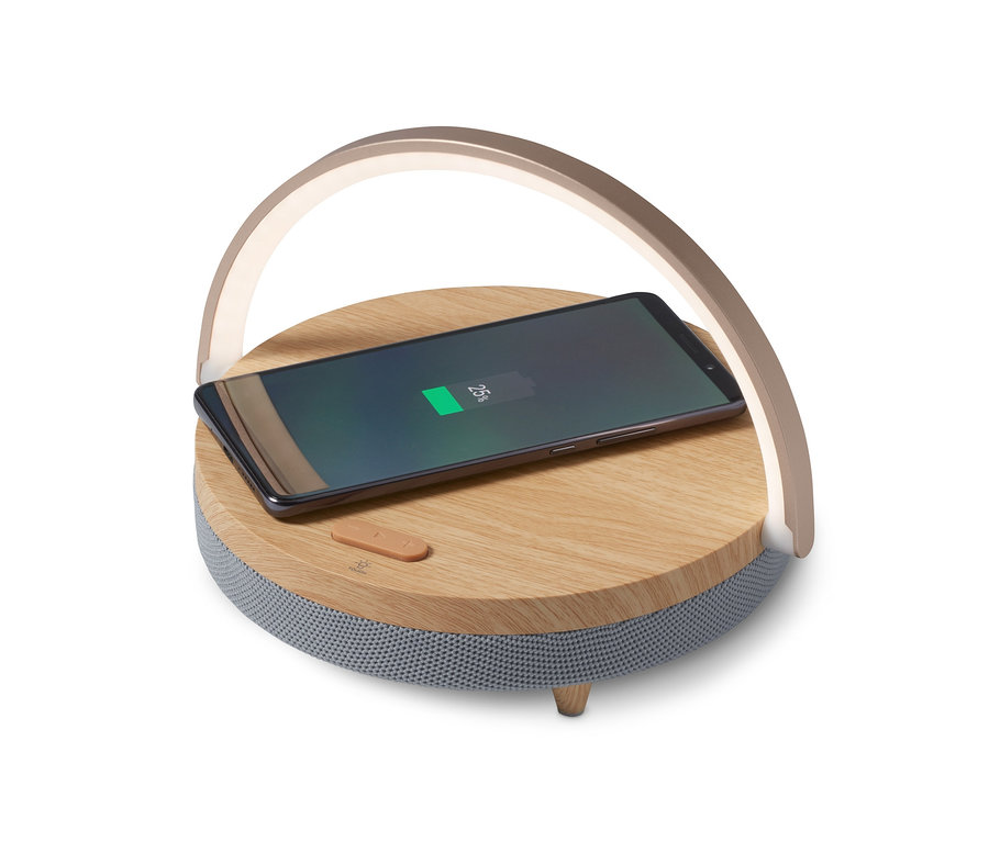 Un téléphone portable se recharge sur un haut-parleur Bluetooth avec chargeur sans fil et veilleuse LED.