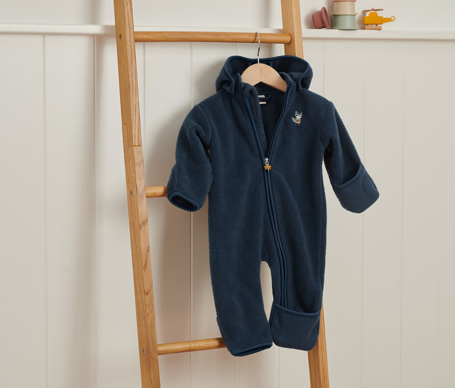 Une combinaison en polaire bleu marine est suspendue à une échelle en bois.