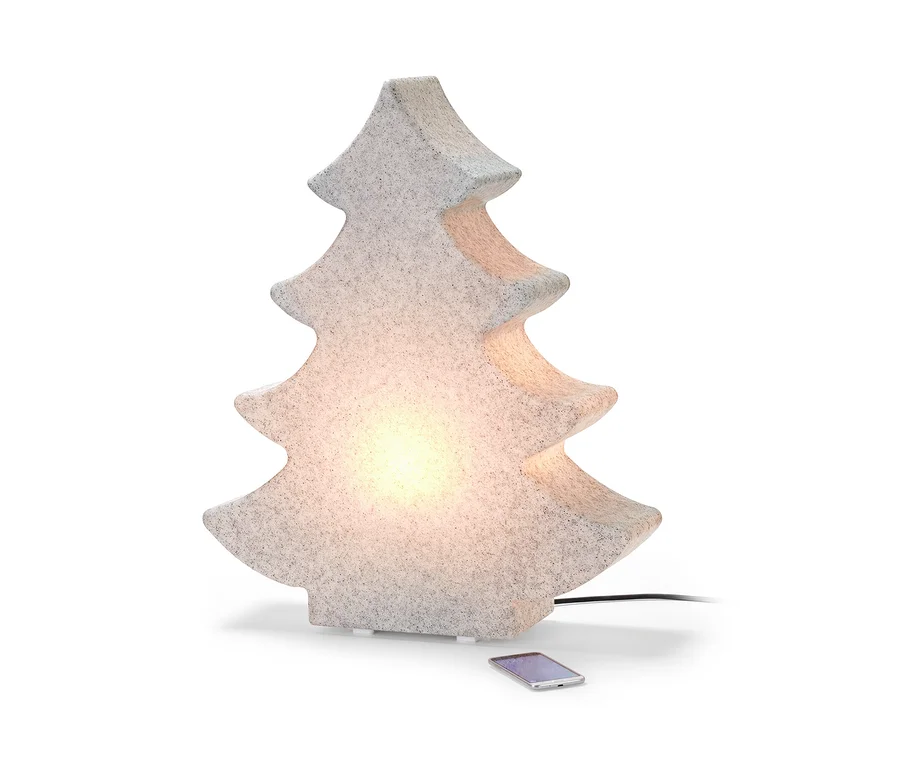 Une lampe d’extérieur LED Smart « Sapin » illuminée est posée sur le sol à côté d’un téléphone portable.