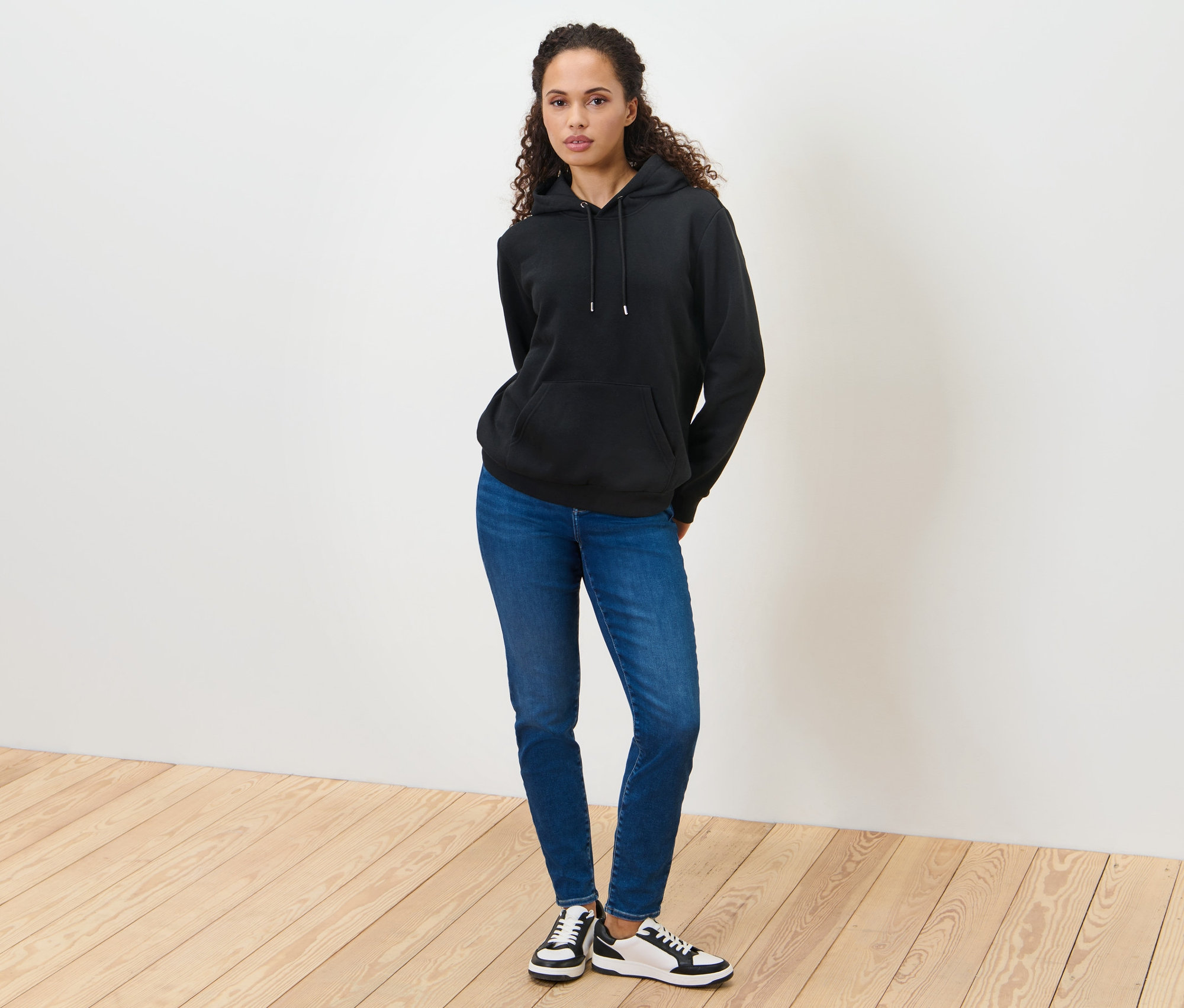 Femme debout portant un sweat à capuche noir.