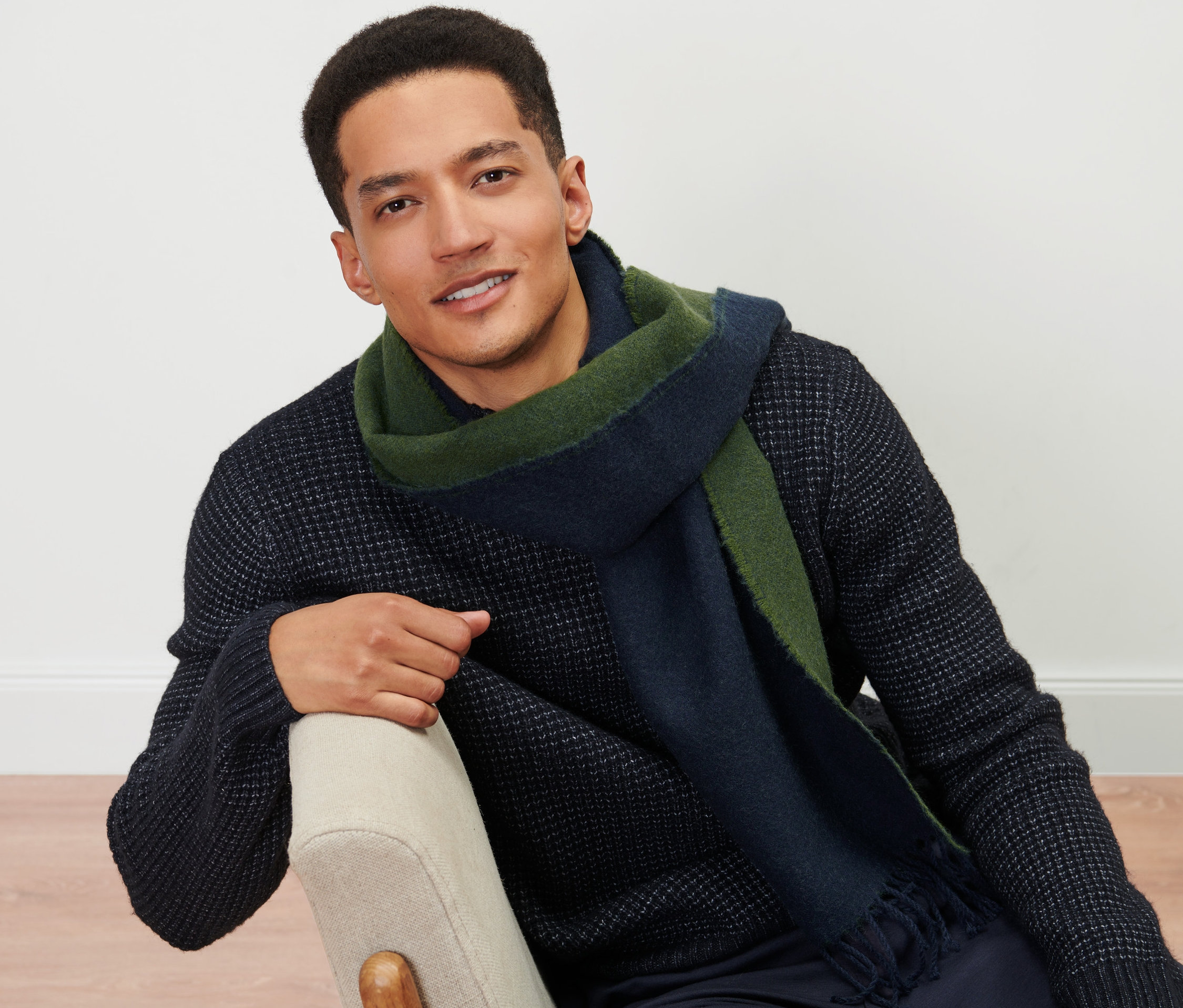 Un homme est assis sur une chaise et porte une écharpe tissée.