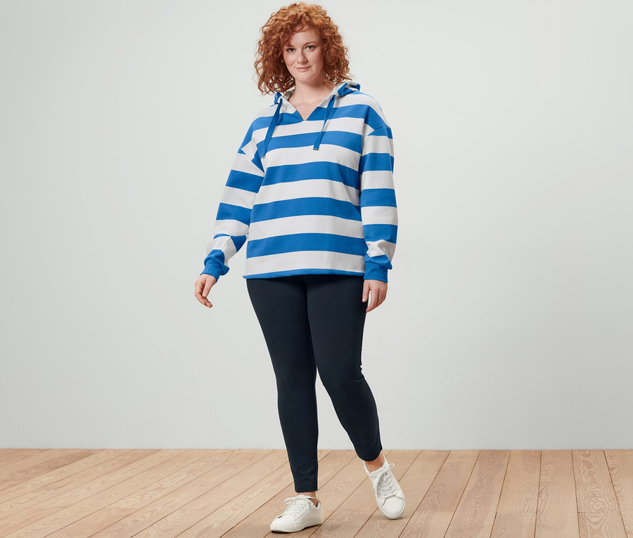 Rousse posant en sweatshirt à capuche à rayures et legging heavy noirs.