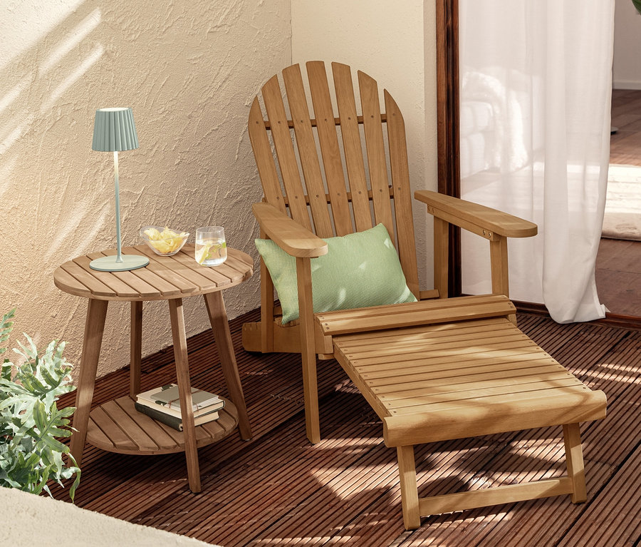 Une chaise de jardin Adirondack avec repose-pieds extensible se trouve à côté d'une table d'appoint à 2 niveaux « Lenja » sur laquelle se trouvent deux lampes de table à LED sans fil vert sauge.