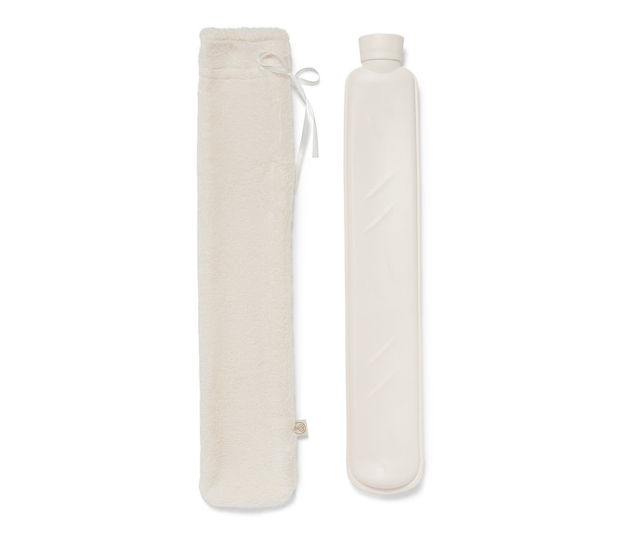 Une bouillotte tube et une housse en peluche sont posées l'une à côté de l'autre.