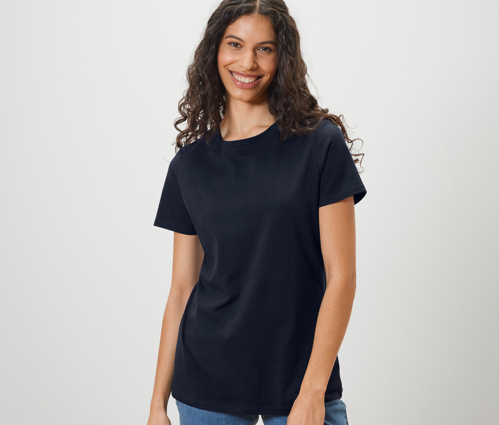 Femme portant un t-shirt basique bleu foncé et un jean.